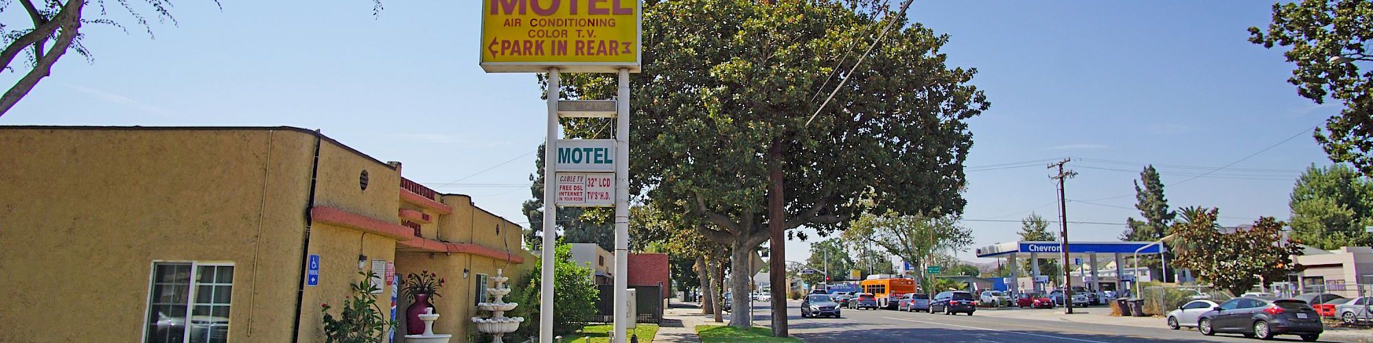 The image shows a street with a motel on the left and cars on the road. A yellow 