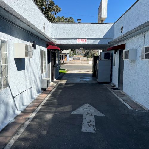 An alley between two white buildings, with windows, air conditioning units, and a painted arrow pointing forward on the ground.