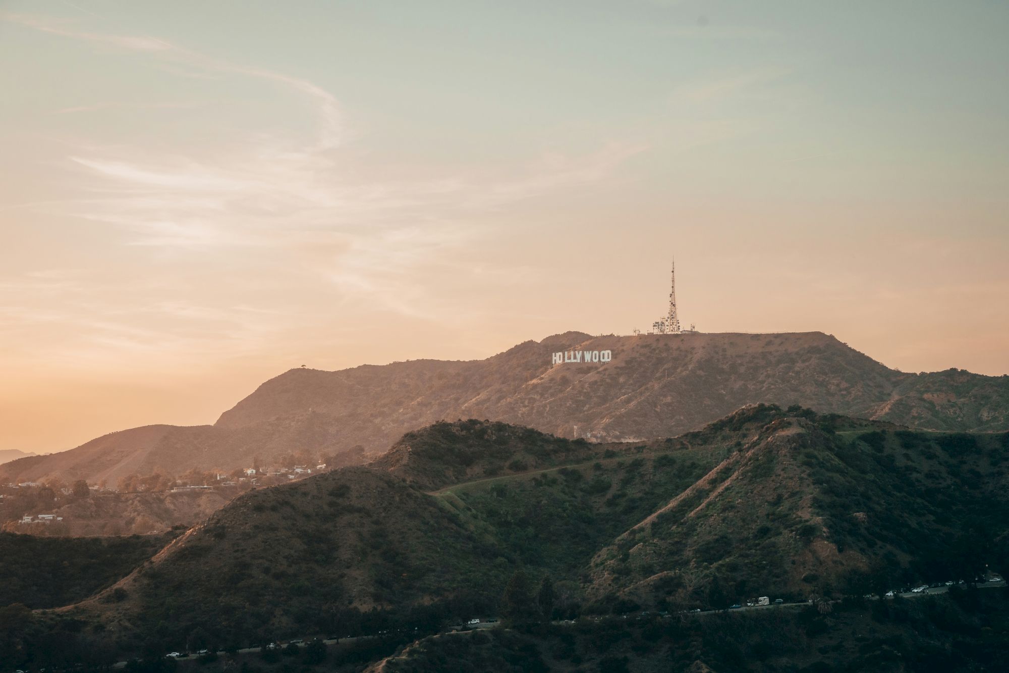 The image shows a landscape view with hills and the famous Hollywood sign in the distance under a serene sky.